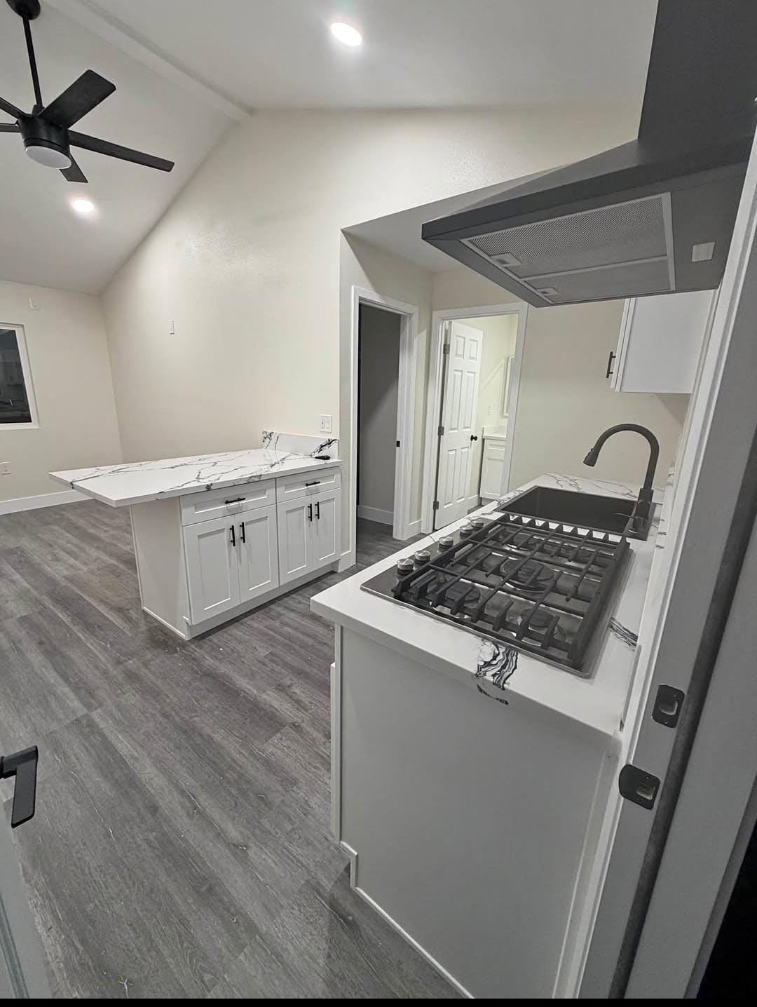Finished ADU kitchen with white cabinets, island and open living area
