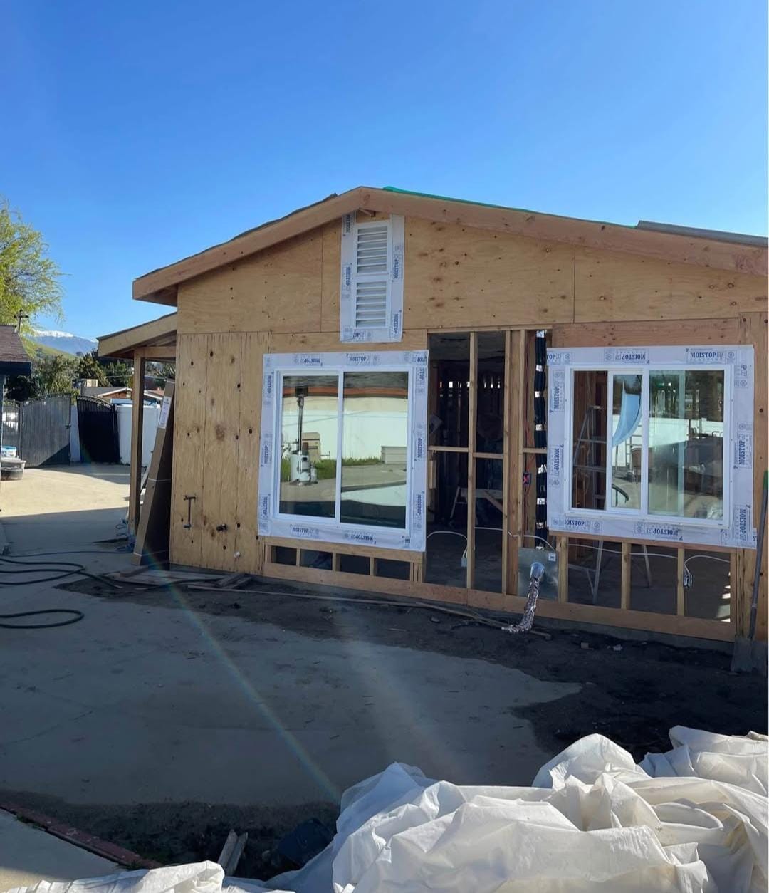 Detached ADU under construction with framing, sheathing and new windows